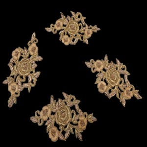 May include: Four gold embroidered floral appliques with a detailed design. Each applique features a central rose surrounded by smaller flowers and leaves. The appliques are set against a black background.