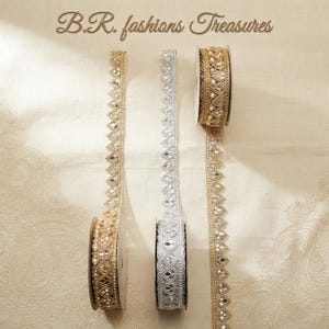 May include: Three spools of decorative trim featuring intricate embroidery and embedded reflective mirror accents. Two spools are gold-toned and one is silver-toned. The text B.R. fashions Treasures is visible at the top of the image.