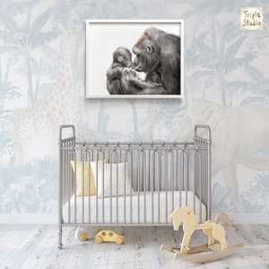May include: A black and white illustration of a gorilla mother and baby cuddling. The image is framed in a white frame and is hanging on a wall with a blue and white jungle wallpaper.