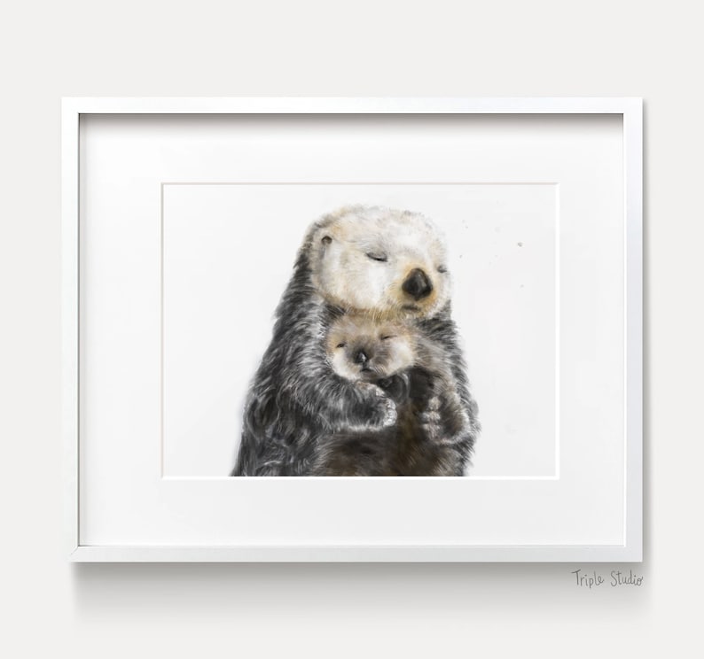 May include: A framed watercolor print featuring two sea otters. The larger otter, with a light beige face and dark fur, embraces a smaller otter. Both otters have their eyes closed, suggesting a peaceful moment. The print is set in a white frame.