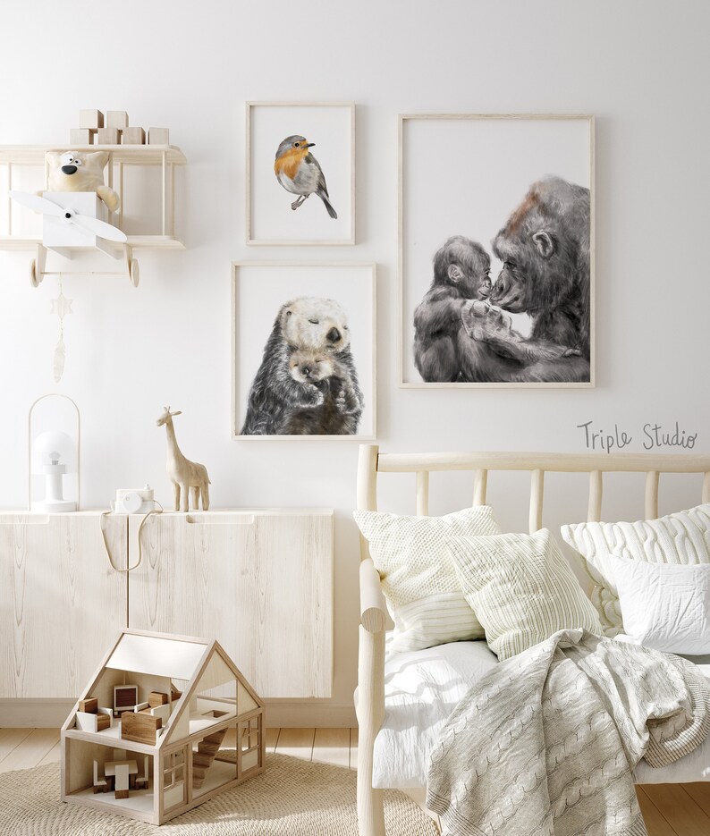 May include: Three framed animal illustrations, a robin, a sea otter, and a gorilla with a baby gorilla. The illustrations are hanging on a white wall in a nursery or child's room.