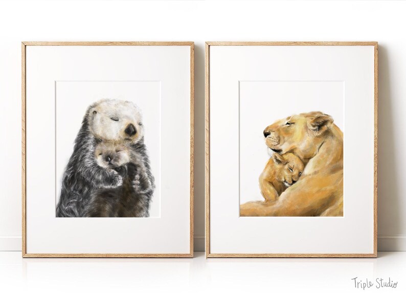 May include: Two framed art prints. One features a watercolor illustration of a sea otter cuddling its pup. The other depicts a lioness embracing her cub. Both artworks are in wooden frames, perfect for nursery or home decor.