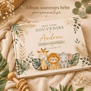Peut inclure: Un album souvenir pour bébé rectangulaire à couverture crème orné d'illustrations aquarelles d'une girafe, d'un lion et d'un éléphant entourés de feuilles vertes. Le texte indique : MON LIVRE SOUVENIRS, Aodren, Les premiers moments de ma vie, 22 mai 2023.