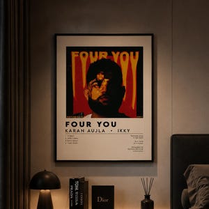 Può includere: Un poster incorniciato con il testo "FOUR YOU" e i nomi "KARAN AUJLA • IKKI" è appeso sopra un comodino. La stanza presenta un'estetica moderna con una lampada nera, libri e una candela.