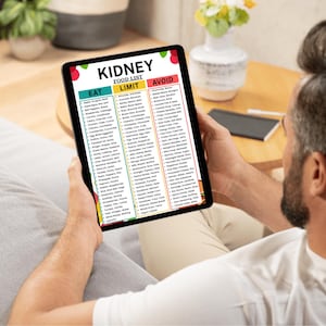 May include: A person holding a black tablet displaying a "KIDNEY FOOD LIST". The list categorizes foods into "EAT", "LIMIT", and "AVOID" sections. The tablet is held in front of a neutral background.