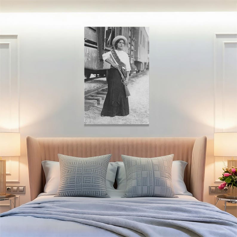 May include: Black and white print of a woman in a long skirt and hat, holding a rifle. She stands near a train car on railroad tracks. The image is a vintage photograph, likely from the early 20th century.