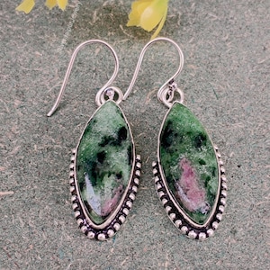 Puede incluir: Un par de pendientes de plata con piedras preciosas verdes y rosas en forma de lágrima. Las piedras están engastadas en un bisel de plata con un borde de cuentas. Cierre de gancho.