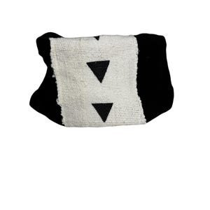 May include: A black and white decorative pillow with a geometric design. The pillow features a central white panel with two black triangles and is framed by black fabric.