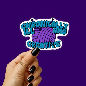 Puede incluir: Una pegatina con el texto "Chronically Ill and Creative" en una fuente retro. El diseño incluye una bola de hilo morada con agujas de tejer. La pegatina está sobre un fondo morado.