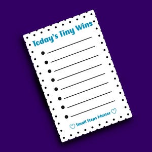 May include: A white notepad with black polka dots and lines for writing. The notepad has the text "Today's Tiny Wins" in blue at the top and "Small Steps Matter" at the bottom. The background is a dark purple.