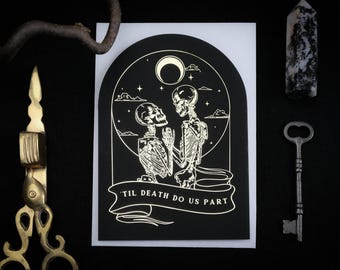 May include: Black and white illustration of two skeletons embracing under a crescent moon and stars, with the text "Til Death Do Us Part" on a banner. A key, a decorative stone, and a brass object are also in the image.