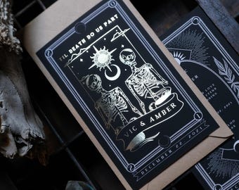 May include: Gothic-themed wedding invitations in black and tan. The design includes a skeleton couple, celestial motifs, and the phrase "Til Death Do Us Part". The names "Vic & Amber" and the date "December 22, 2021" are also displayed.