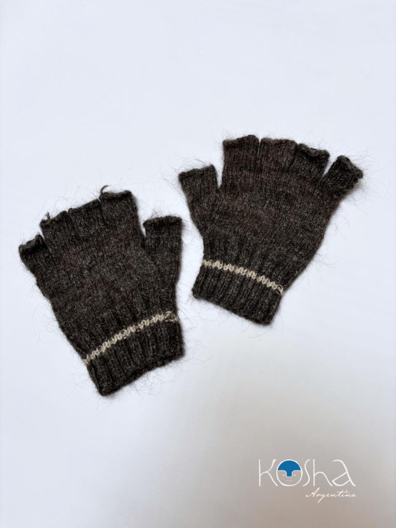 Puede incluir: Un par de guantes sin dedos hechos de un material de punto difuso de color marr&oacute;n oscuro. Cada guante presenta un pu&ntilde;o acanalado con una franja horizontal de color beige claro cerca de la mu&ntilde;eca. El texto "Kosha Argentina" aparece abajo.