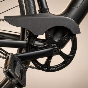 May include: A matte black bicycle drivetrain featuring a carbon drive belt system, a circular chainring with the text Carbon Drive CDX, a black plastic chain guard, a pedal, and a portion of the rear tire with visible tread patterns.
