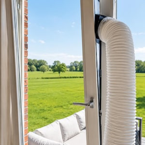 Puede incluir: Una manguera de escape flexible y blanca para aire acondicionado está instalada a través de un marco de puerta blanco parcialmente abierto. La manguera es estriada y se extiende verticalmente, conectándose a un kit de sellado negro en la puerta.