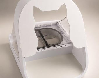 Può includere: Una mangiatoia automatica bianca per animali domestici con una sagoma a forma di gatto ritagliata sul pannello frontale. Il dispositivo include un coperchio in plastica trasparente che copre una ciotola a due scomparti con inserti grigi.