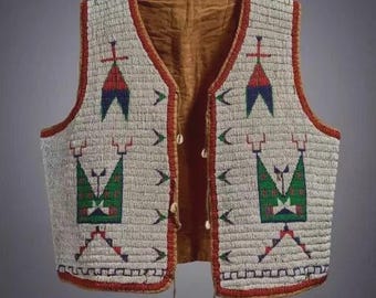 Puede incluir: Un chaleco con cuentas con un fondo color crema y diseños geométricos en rojo, verde y azul. El chaleco tiene un forro marrón y está ribeteado con cuentas rojas. El chaleco está abierto por delante y tiene unos botones de concha.