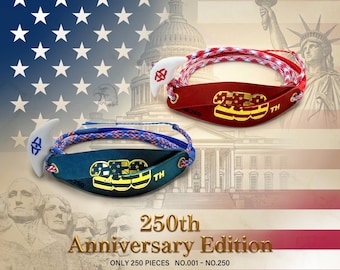 Peut inclure: Deux frondes, une rouge et une bleue, avec des cordons tressés et des languettes de libération blanches. La fronde rouge porte le texte 250th en or, la bleue en jaune. Le texte 250th Anniversary Edition et The King David Sling est visible.