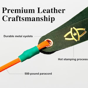 Puede incluir: Una correa de cuero verde oscuro con un logotipo dorado estampado en caliente, un ojal met&aacute;lico duradero y un paracord naranja de 550 libras asegurado con una funda verde. El texto Premium Leather Craftsmanship es visible en la parte superior.