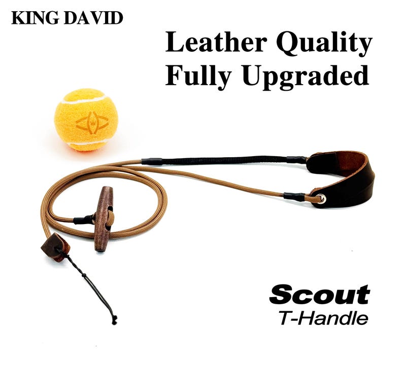 May include: A tan cord leash with a brown wooden T-handle and a dark brown leather wrist loop, accompanied by a yellow tennis ball. The text reads KING DAVID, Leather Quality Fully Upgraded, and Scout T-Handle on a white background.
