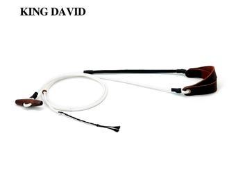 Peut inclure: Une fronde de marque King David composée d'une corde blanche, d'une poche à projectile en bois brun foncé et d'une boucle de doigt en cuir brun foncé. L'objet comprend des accents en corde noire et une poignée à bascule en bois.