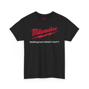 May include: Black t-shirt with the Milwaukee logo in red, featuring the brand name and a lightning bolt design. Below the logo, the text reads "Nothing but HEAVY DUTY."