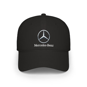 May include: Black baseball cap featuring the Mercedes-Benz logo. The logo is a silver three-pointed star inside a circle, with the brand name below in white text. The cap has a curved brim and a structured crown.