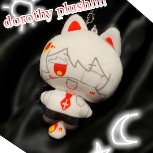 May include: White plush doll with red accents on the ears and face, wearing a white shirt and black pants. The doll has a red tie with a cross. The text "dorothy plush!!!" is above the doll.