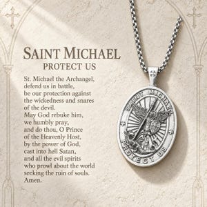 May include: A silver-toned oval pendant necklace featuring an embossed image of Saint Michael defeating a dragon. The pendant is inscribed with the text Saint Michael Protect Us and hangs from a silver chain. The text of the Saint Michael prayer is printed to the left of the pendant.