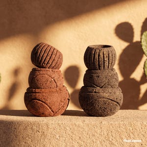 Peut inclure: Deux piles de trois bols en pierre poreuse et texturée. La pile de gauche est brun rougeâtre et celle de droite est gris anthracite foncé. Chaque bol présente des lignes verticales ou des motifs courbes gravés. Le texte FiveCosmos est visible.