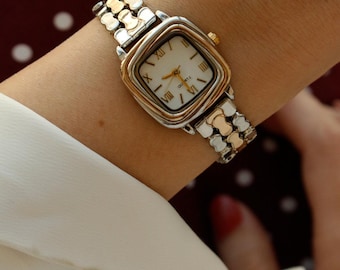 Reloj cuadrado bicolor para mujer, esfera con números romanos en tonos dorado y plateado.