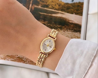 Elegante reloj de pulsera ovalado en tono dorado para mujer.