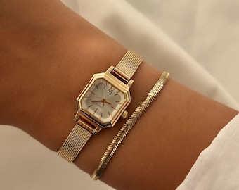 Reloj minimalista en tono dorado para mujer, con correa de malla.