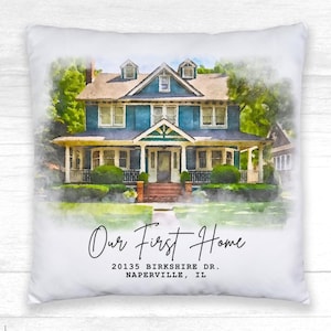 May include: White square pillow featuring a watercolor painting of a blue house with a porch and green landscaping. The text "Our First Home" and address are printed below the image. The pillow is a home decor item.