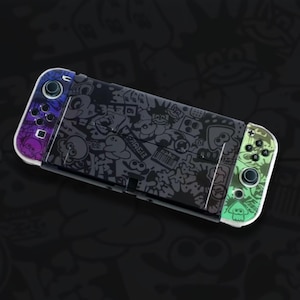 May include: A Nintendo Switch console with a custom skin featuring a black and grey design with cartoon characters and splatters. The left controller has purple and blue gradients, the right has green gradients.