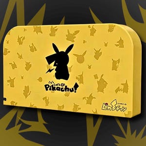 Puede incluir: Estuche rectangular amarillo con una silueta negra de Pikachu y un rayo, además del texto "Let's Go Pikachu!". El estuche tiene un patrón repetitivo de siluetas de Pikachu. El fondo es amarillo oscuro con diseños de rayos.