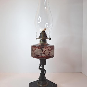 Lámpara de aceite victoriana antigua de cristal tallado color rubí con figura femenina y base de mármol.
