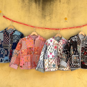 Könnte beinhalten: Vier gesteppte Jacken mit Patchwork-Mustern hängen vor einer gelben Wand. Jede Jacke hat ein einzigartiges Design mit verschiedenen Farben und Mustern. Die Jacken werden an Holzbügeln aufgehängt, die an einer roten Kette befestigt sind.