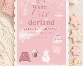 Op de afbeelding: Een roze uitnodiging met de tekst "It's a Winter One derland" voor Ellie's eerste verjaardag. De uitnodiging bevat illustraties van winterse items zoals een trui, een sneeuwpop en koekjes. Roze wanten, een muts en een sjaal omringen de uitnodiging.