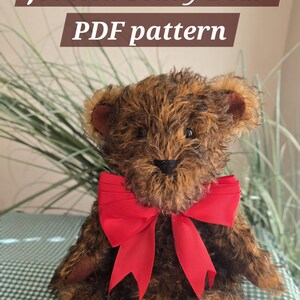 Puede incluir: Un oso de peluche de pelo rizado marrón y negro con un gran lazo rojo atado al cuello. El oso tiene almohadillas en las patas e interior de las orejas de tela marrón oscuro. El texto "Jointed Teddy Bear PDF pattern" aparece en blanco.