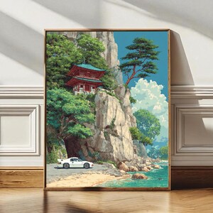 Può includere: Stampa artistica incorniciata raffigurante un paesaggio costiero con un'auto sportiva bianca su una strada. Un edificio tradizionale rosso e verde si trova su una scogliera, circondato da alberi verdi e cielo blu.