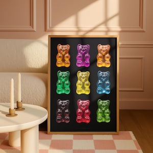 Pode incluir: Uma impressão emoldurada com nove ursinhos de goma coloridos dispostos sobre um fundo preto. Os ursinhos de goma são de várias cores, incluindo laranja, roxo, amarelo, verde, azul e vermelho. A moldura é dourada.