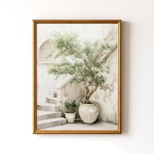 May include: A framed print featuring a serene outdoor scene. A small tree in a large, ornate pot sits beside a set of stone stairs. The print has a gold frame and a neutral color palette, with a focus on the tree and architectural details.
