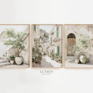 May include: Set of three framed art prints featuring Italian street scenes. The prints showcase buildings with arched doorways, staircases, and potted plants. The color palette is soft, with beige, green, and brown tones. The Lumen Gallery logo is at the bottom.