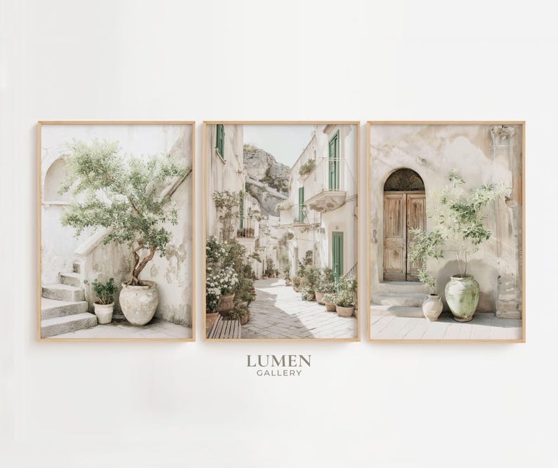 May include: Set of three framed art prints featuring Italian street scenes. The prints showcase buildings with arched doorways, staircases, and potted plants. The color palette is soft, with beige, green, and brown tones. The Lumen Gallery logo is at the bottom.