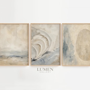 Puede incluir: Un conjunto de tres láminas de arte mural abstracto enmarcadas con pinceladas texturizadas en tonos beige, crema y azul apagado. La obra muestra formas orgánicas y efectos de pintura en capas. El texto LUMEN GALLERY aparece bajo las láminas.