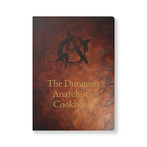 May include: A hardcover book with a brown, textured cover. The cover features a black anarchy symbol and the gold text "The Dungeon Anarchist's Cookbook". The book has a vintage, worn appearance.