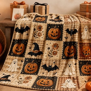 Op de afbeelding: Een patchwork quilt met een herhalend patroon van vierkanten met een Halloween-thema. Het ontwerp bevat illustraties van oranje pompoenen, witte geesten, zwarte vleermuizen, puntige heksenhoeden en bruine bloemmotieven op ruitjesachtergronden.