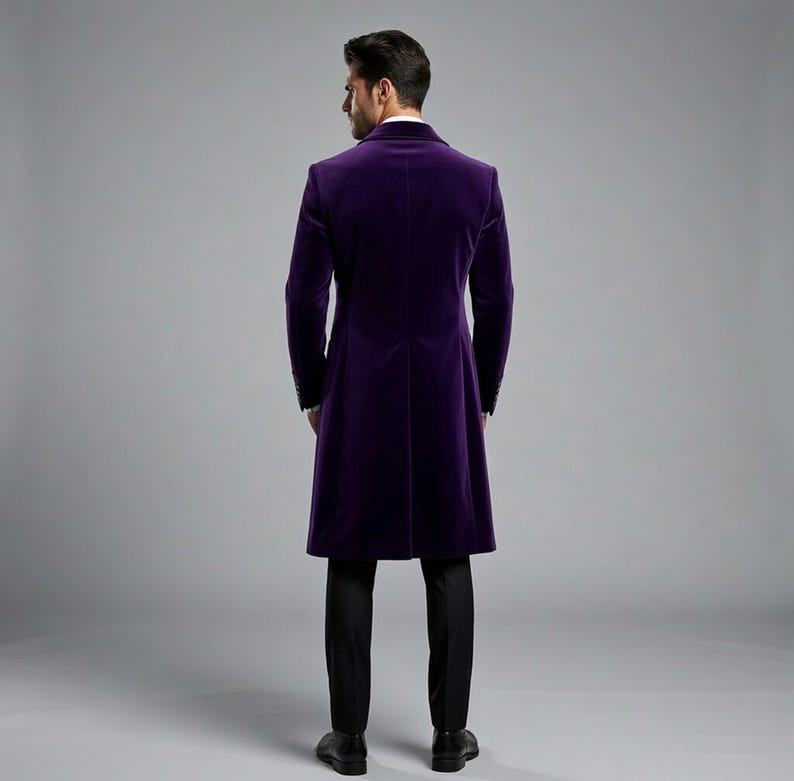 Pu&ograve; includere: Un lungo cappotto di velluto viola scuro dal design classico. Il cappotto presenta una vestibilit&agrave; sartoriale, maniche lunghe e chiusura con bottoni. La persona indossa pantaloni neri e scarpe nere.