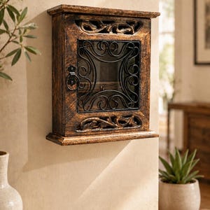 Può includere: Un mobile in legno rustico, montato a parete, con finitura scura. L'armadietto presenta una porta a vetri incorniciata da decorazioni in ferro battuto. Dettagli intagliati adornano la parte superiore e inferiore, aggiungendo fascino vintage.